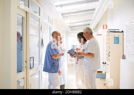 Sorridente operatori sanitari che discutono mentre si trovano in corridoio all'ospedale Foto Stock