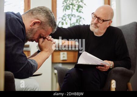 L'uomo depresso piangendo mentre il terapeuta lo consolava al centro della comunità Foto Stock