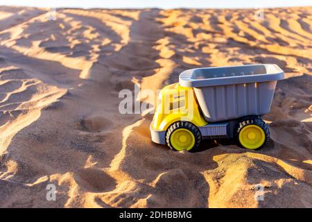 Giocattolo giallo carico e scarico camion sulla sabbia nel deserto. Foto Stock