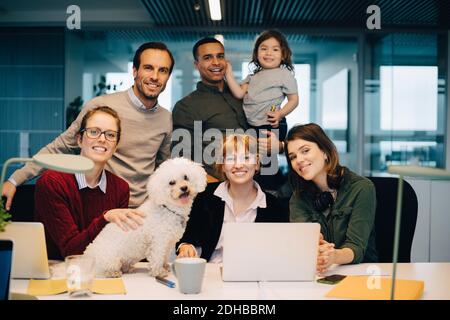Ritratto di squadra sorridente di affari con il capretto ed il cane a. ufficio creativo Foto Stock
