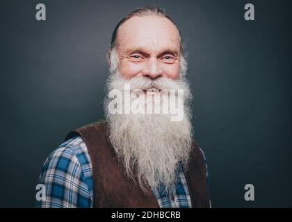 Ritratto di uomo sorridente con barba bianca e baffi su sfondo grigio Foto Stock