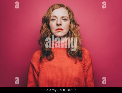 Ritratto di donna sicura in cima arancione su sfondo rosa Foto Stock