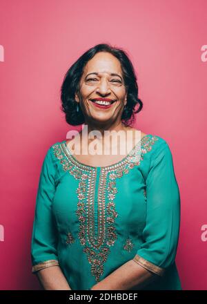 Ritratto di donna anziana sorridente che indossa il salwar kameez su rosa sfondo Foto Stock