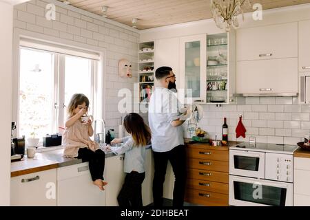 Padre e figlia lavorano al banco mentre la ragazza mangia cibo in cucina Foto Stock