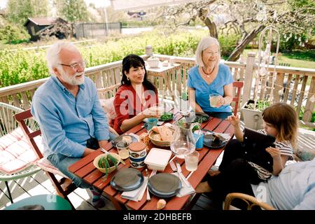 Famiglia multigenerazionale che gode di cibo al tavolo nel patio Foto Stock