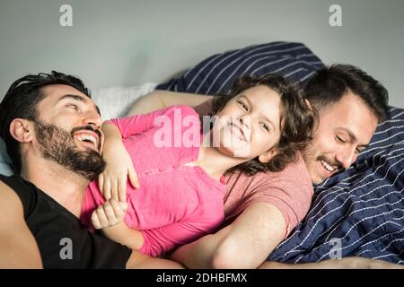 Figlia allegra che gioca con i padri sul letto in camera da letto a. casa Foto Stock