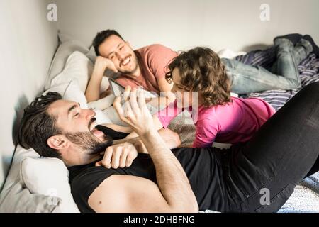 I padri allegri giocano con la figlia mentre si sdraia a letto a. casa Foto Stock