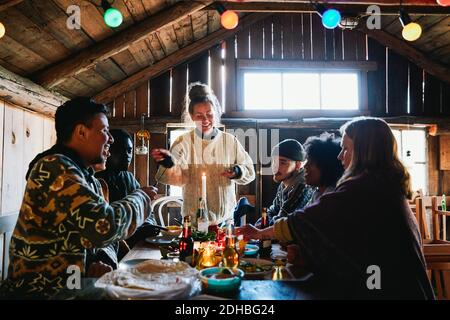 Una giovane donna sorridente che parla mentre si gusta il pasto con gli amici cottage Foto Stock