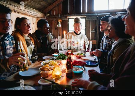 Amici di sesso maschile e femminile che parlano mentre si mangiano in cottage Foto Stock