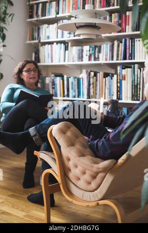 Terapista femminile che parla con l'uomo maturo da libreria a casa ufficio Foto Stock