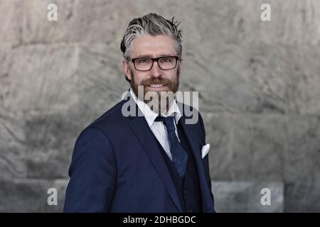 Ritratto di uomo d'affari sorridente in tuta in piedi contro il muro Foto Stock