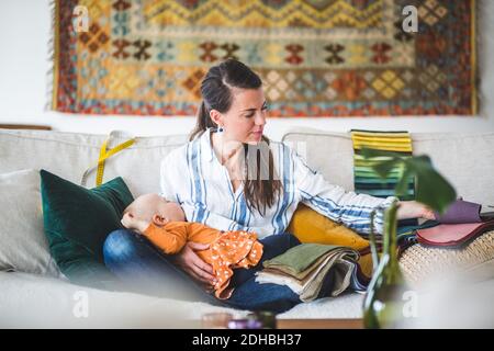 Donna design professionale con figlia addormentata guardando il campione di tessuto in ufficio a casa Foto Stock