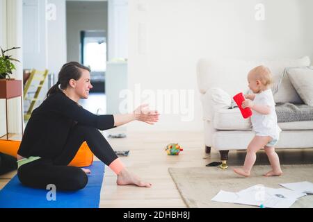 Vista laterale della madre gesturing mentre chiama figlia in vita camera in ufficio a casa Foto Stock