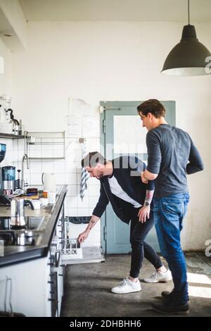 Tutta la lunghezza dei programmatori maschi che si levano in piedi in cucina al creativo ufficio Foto Stock