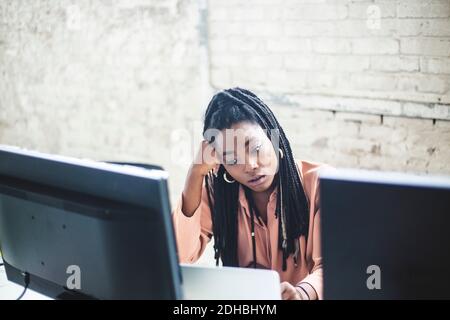 Visualizzazione ad alto angolo di una giovane femmina di computer hacker codifica a. scrivania in ufficio Foto Stock