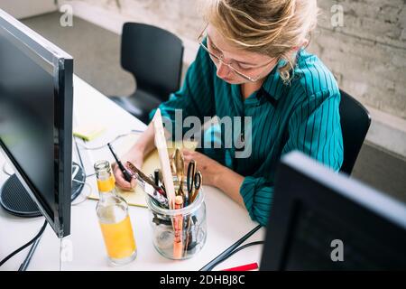 Visualizzazione ad alto angolo di una scrittura professionale SICURA per l'IT femminile area per appunti alla scrivania in un ufficio creativo Foto Stock