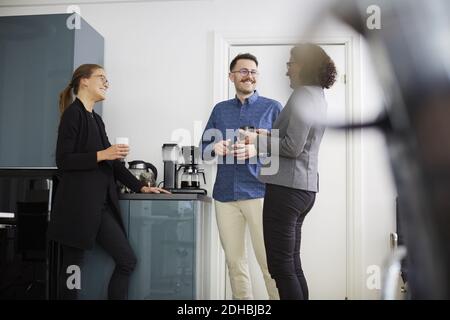 Sorridi i colleghi aziendali che hanno il caffè mentre parlano in ufficio Foto Stock