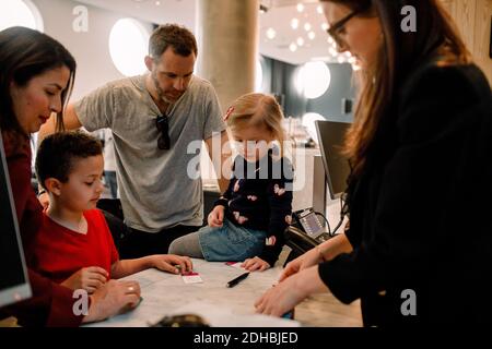 La receptionist dà le chiavi alla famiglia alla reception dell'hotel Foto Stock