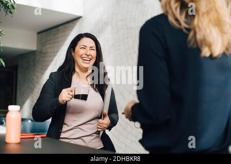 Donna d'affari sorridente che ha il caffè mentre parla con il collega alla conferenza Foto Stock