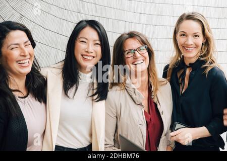 Ritratto di felici donne multietniche professionisti del business in piedi contro il muro Foto Stock