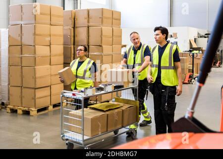 Colleghi multietnici che spingono il carrello al magazzino di distribuzione Foto Stock