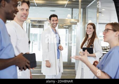 Sorridente team sanitario multietnico che discute presso la hall dell'ospedale Foto Stock