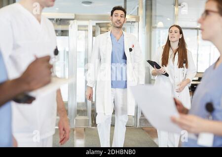 Team sanitario multietnico che discute nella hall dell'ospedale Foto Stock