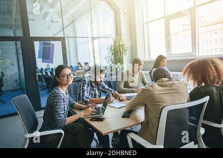 Un team di giovani lavoratori in ufficio che lavorano alla scrivania Foto Stock