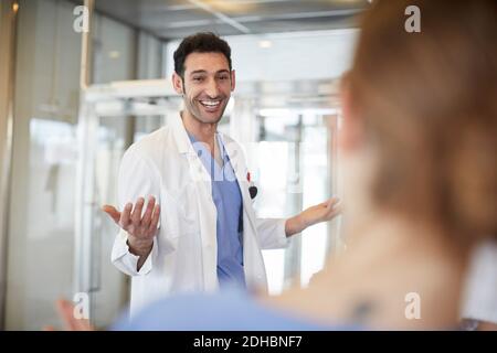 Allegro giovane medico maschile gesturing a infermiera femminile mentre in piedi nella hall dell'ospedale Foto Stock