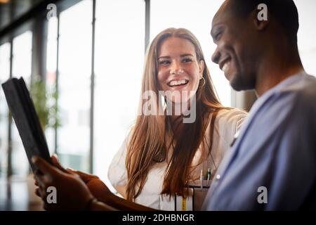 Infermieri sorridenti che parlano di tablet digitale in corridoio all'ospedale Foto Stock