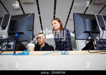 Visualizzazione ad angolo basso degli amici che guardano i computer dell'università Foto Stock