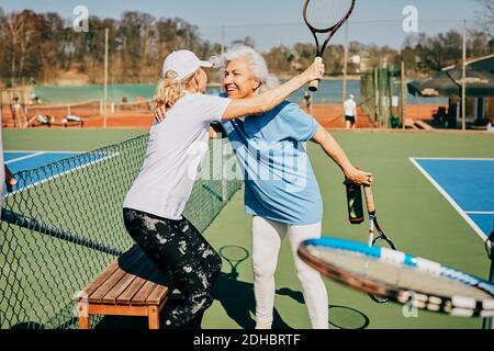 Felice femmina senior amici saluto al campo da tennis durante l'estate Foto Stock