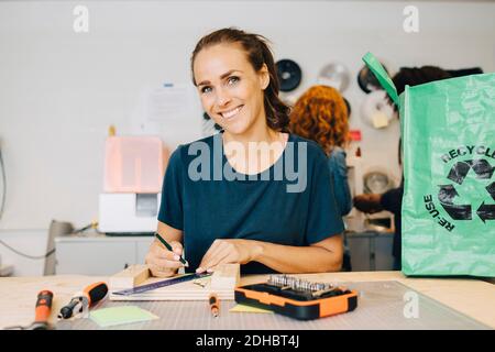 Ritratto di sorridente tecnico che lavora seduto al banco di lavoro in ufficio creativo Foto Stock
