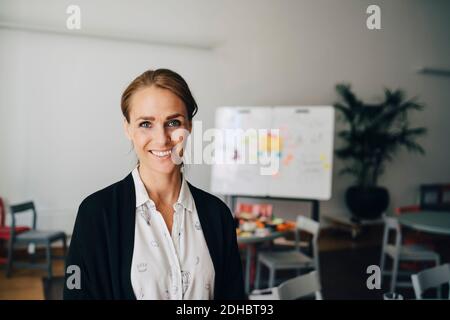 Ritratto di una donna d'affari sorridente e mid adulta in piedi in ufficio creativo Foto Stock