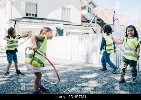 Tutta la lunghezza degli studenti che giocano con i cerchi di plastica nel parco giochi Foto Stock