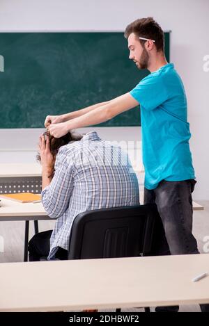 Due alunni maschi in concetto di bullismo in classe Foto Stock