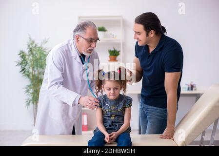 Giovane padre e sua figlia in visita al vecchio medico maschile Foto Stock