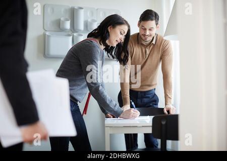 Uomo guardando donna firma carte di nuova casa Foto Stock