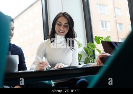 Donna sorridente con l'uomo che firma carte di proprietà nel bene immobile ufficio Foto Stock