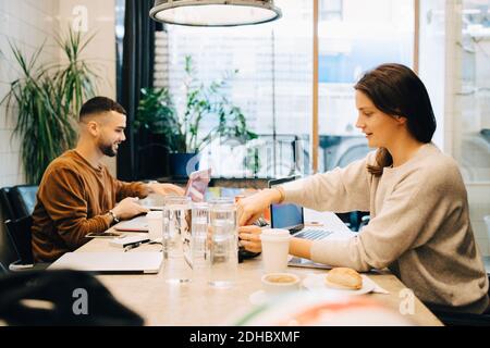 Vista laterale di giovani hacker multietnici maschi e femmine che lavorano alla scrivania in ufficio creativo Foto Stock