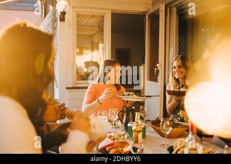 Amici felici che gustano il cibo al tavolo da pranzo in cena festa Foto Stock
