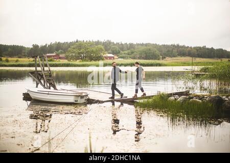 Coppia tenendo le mani mentre camminando verso il molo sopra il lago durante fuga nel fine settimana Foto Stock