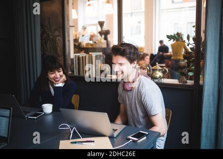 Sorridendo donne e uomini creativi professionisti discutere su laptop a. scrivania in ufficio Foto Stock