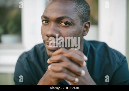 Ritratto di uomo medio-adulto fiducioso con le mani aggrappate Foto Stock