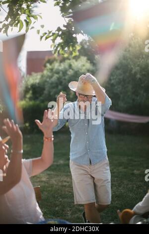 Donna anziana che si aggrappò mentre l'uomo indossa un cappello di paglia e cammina in cortile durante il giorno di sole Foto Stock