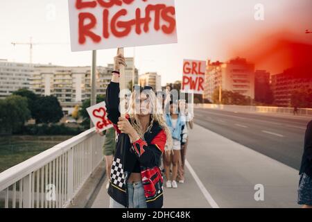 Donne con manifesti che marciano per pari diritti contro cielo in città Foto Stock