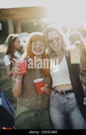 Ritratto di amici felici che si gustano bevande nel festival di musica su giorno di sole Foto Stock