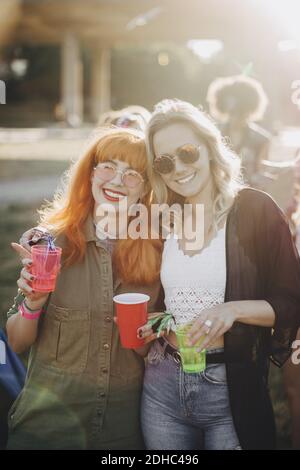 Ritratto di amici maschi sorridenti che gustano un drink in concerto giorno di sole Foto Stock