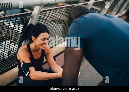 Atleta femminile che mostra il telefono cellulare allo sportivo sul ponte pedonale Foto Stock