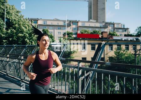 Un'atleta sicura che fa jogging sul ponte in città Foto Stock